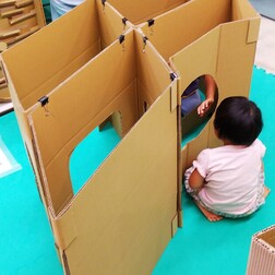 写真:段ボール迷路で遊ぶ子ども